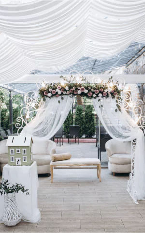 Celebration marquee dressed with white draped fabric, floral garlands and lounge seating